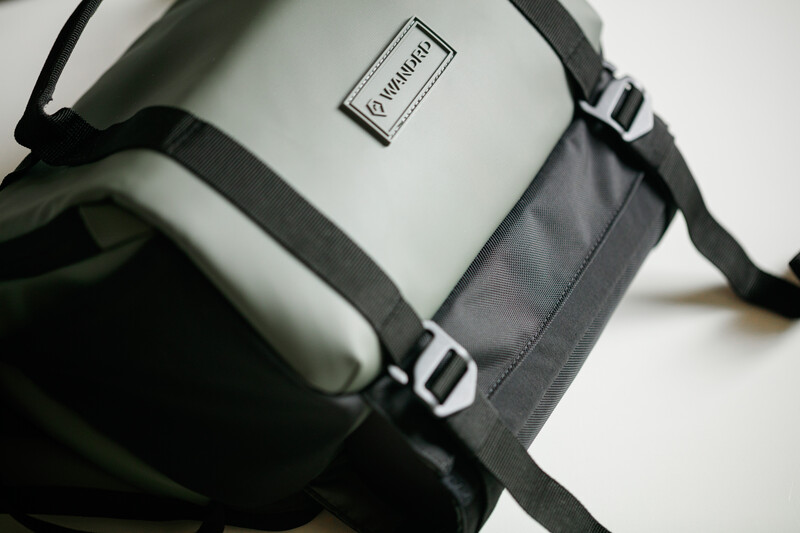 Camera shoulder bag with white and gray fabric panels and black straps with plastic buckles.