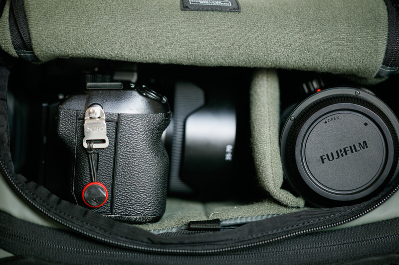 Fujifilm camera gear organized in a padded case with lens cap and rolled fabric strap.