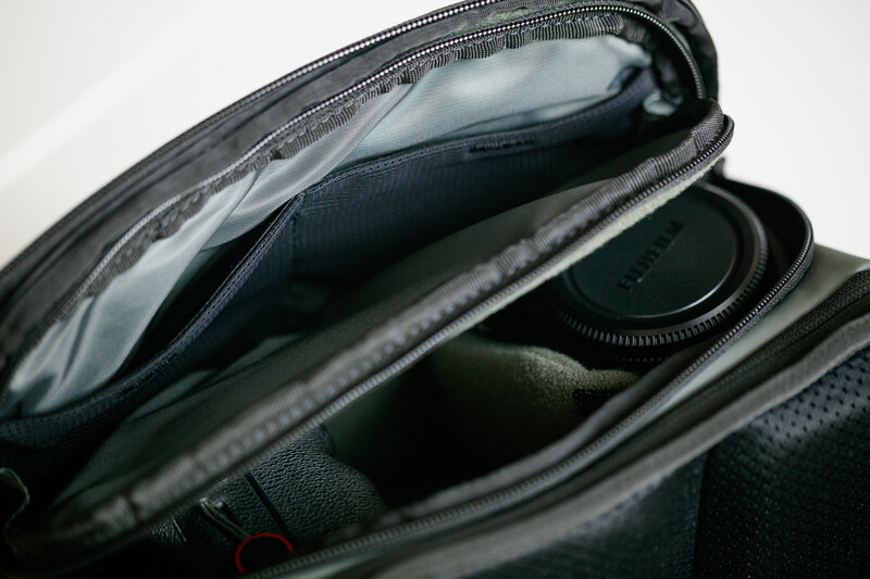 Open camera gear bag displaying lens, filters, and protective compartments with clear organizational pockets.