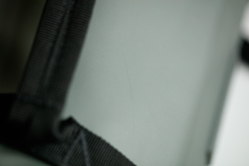 Close-up of black ribbed fabric texture against a light gray background with shallow depth of field.