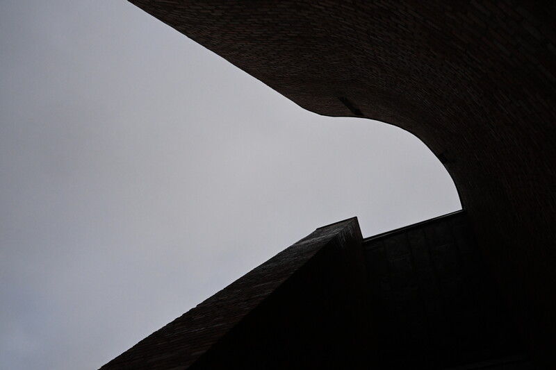Minimalist architectural photograph showing white curved form against dark textured background.