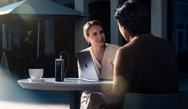Two people conversing across a desk in a modern office setting with natural light from windows.
