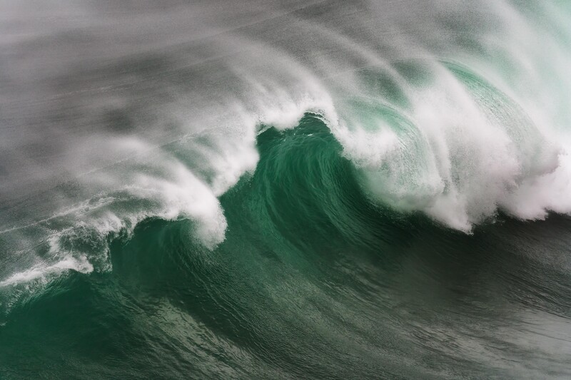 A photograph of a bit wave braking. displaying power, motion and atmosphere 
