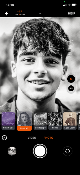 Screenshot of a mobile photo editing app displaying a black and white portrait of a young man with a smile.