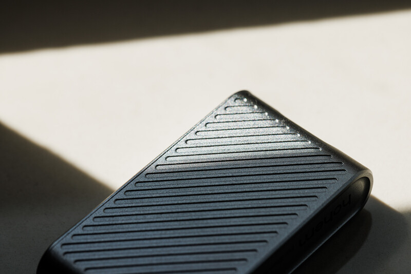 Close-up of a ribbed phone case in dramatic side lighting, creating strong shadows across its textured surface.