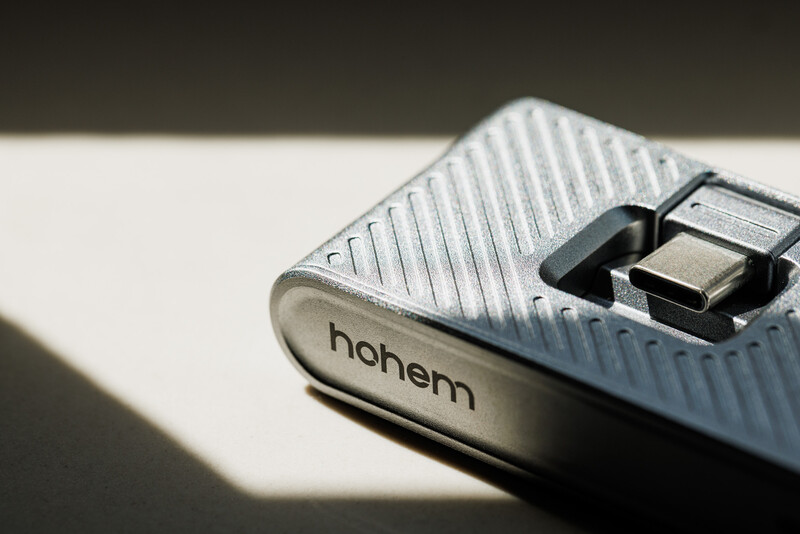 Close-up of a Hoherm camera lens cap with textured surface and detachable center element in harsh sunlight.
