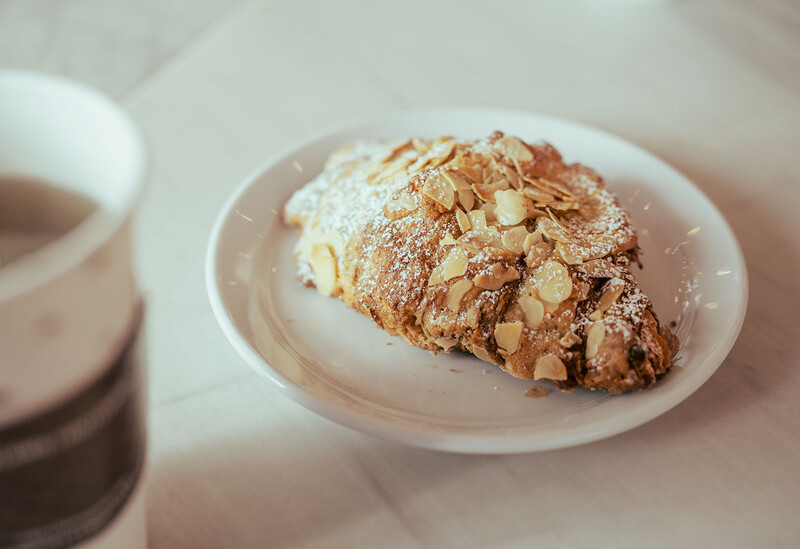 Almond croissant dusted with powdered sugar on a white ceramic plate.
