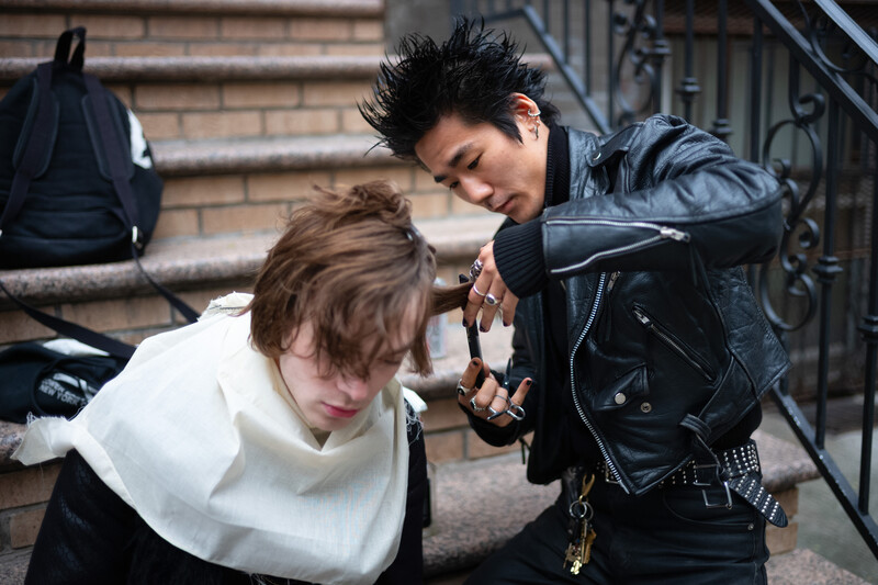 Barber giving friend a haircut outside on apartment building steps