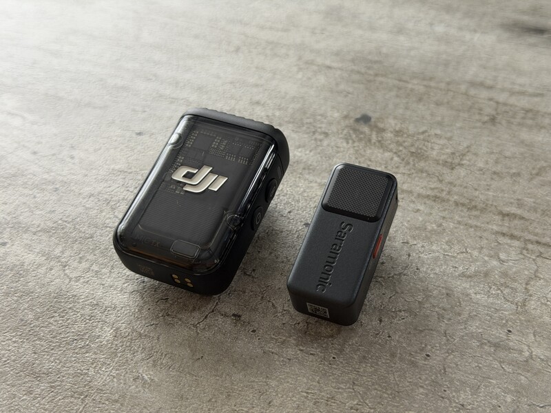 Two compact black action cameras displayed side by side on a concrete surface.