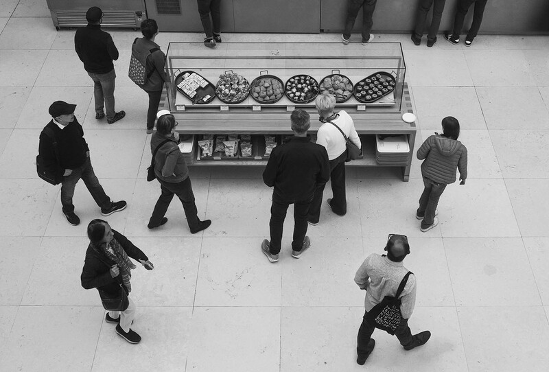 Overhead view of people browsing a display case in a modern tiled interior space.