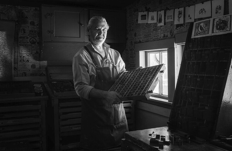 Man holding a solar panel in a workshop lit by natural window light.