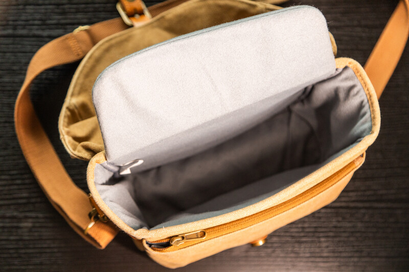 Open tan canvas camera bag displaying padded white and dark gray interior compartments.