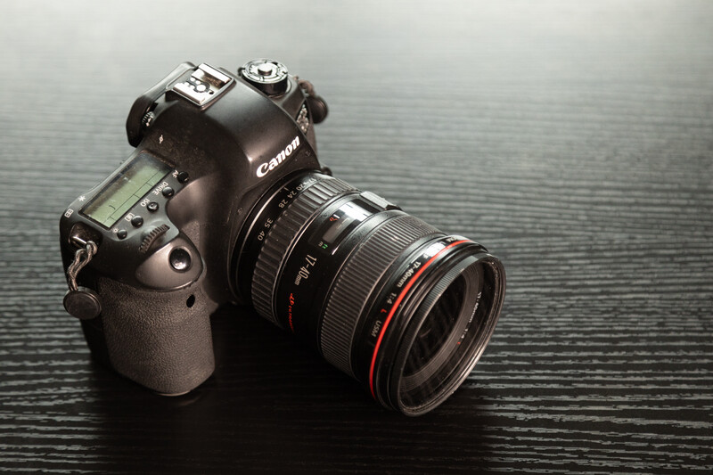 Canon DSLR camera with telephoto lens on dark textured surface.