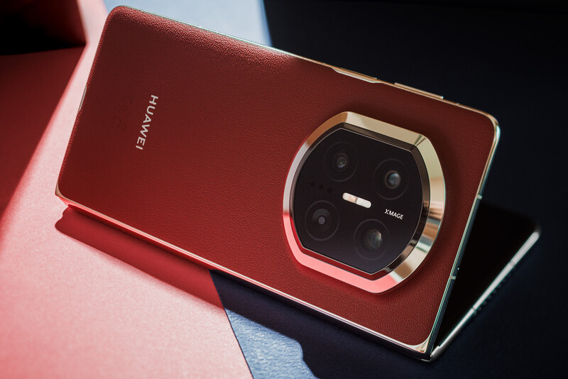 Red smartphone with square camera module featuring four lenses and gold accents, displayed at an angle on a colorful surface.