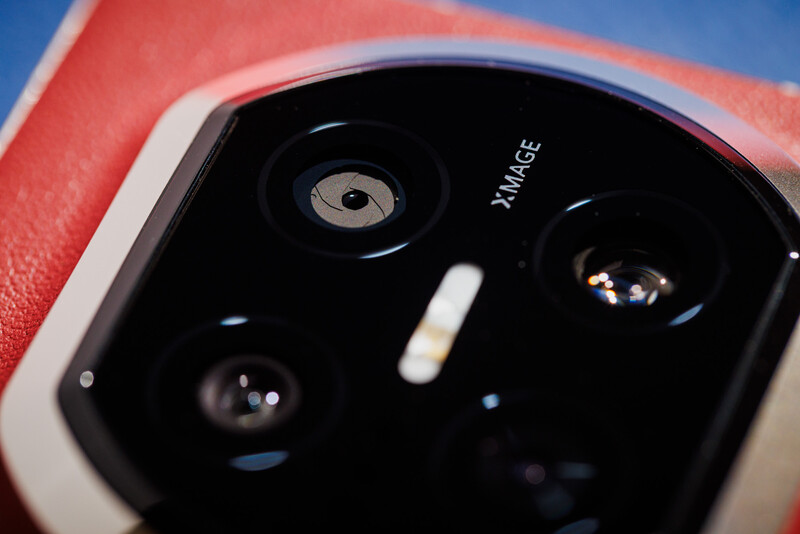 Close-up of a smartphone camera module with multiple lenses against a red device body.