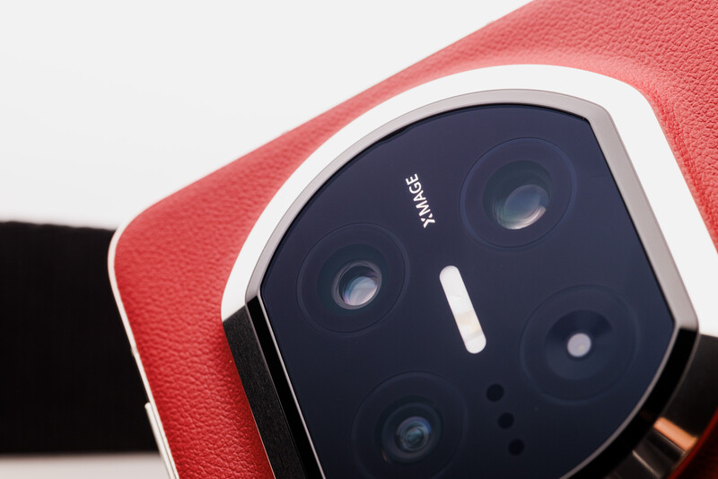 Close-up of a smartphone camera module with multiple lenses on red and black textured material.