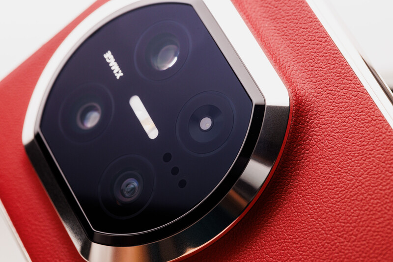 Close-up of a smartphone camera module with four lenses arranged on a red textured case.