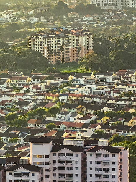 Aerial view of residential apartment buildings nestled among densely packed houses and greenery.