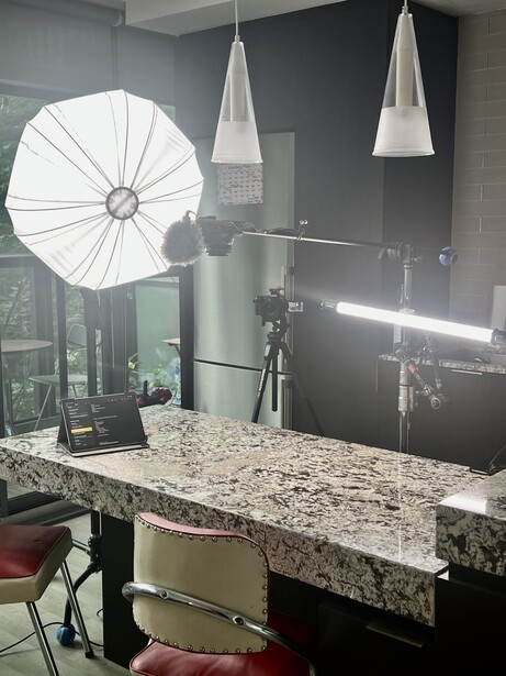 Professional product photography setup with white umbrella reflector, pendant lights, and granite countertop surface.
