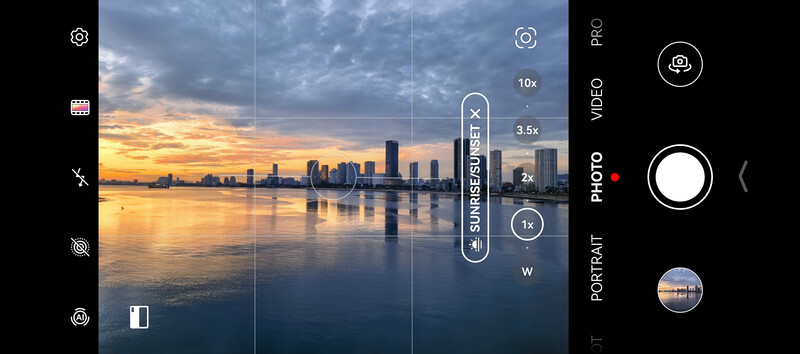 Screenshot of a smartphone camera interface showing a city skyline reflected in water at golden hour.