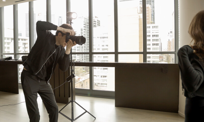 Photographer shooting in a high-rise office with floor-to-ceiling windows overlooking a city skyline.