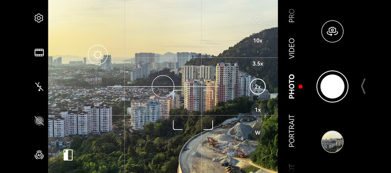 Screenshot of a mobile camera app interface showing a cityscape with zoom controls and photo/video format options.