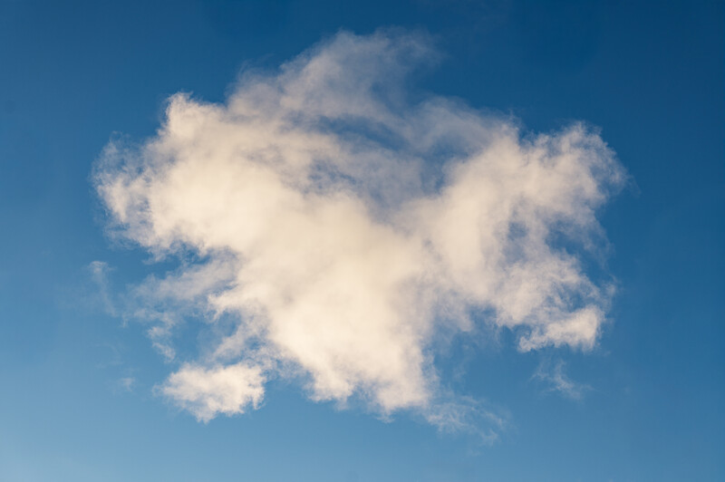 Single white cumulus cloud against clear blue sky.