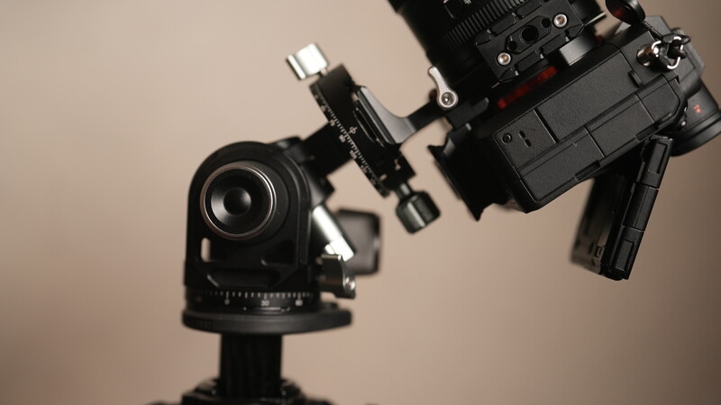 Professional camera rig with telephoto lens and shoulder-mounted stabilizer on gimbal head.