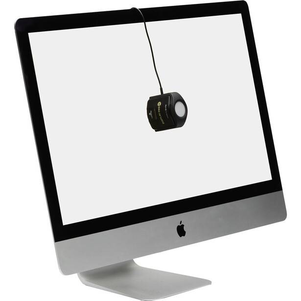 Camera lens suspended by cable above an iMac display on white background.