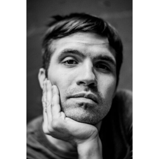Black and white portrait of a man with his hand to his chin in a contemplative pose.