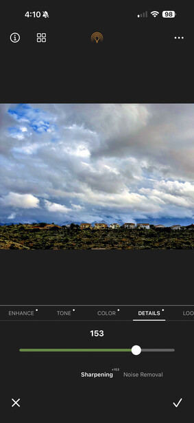 Dramatic sky with dark storm clouds and blue patches above a desert landscape with sparse vegetation.