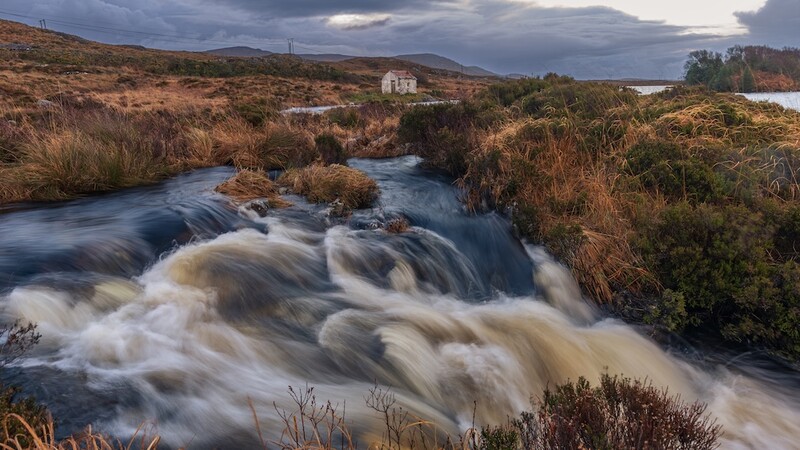 Rushing river with silky water flow in moorland landscape at dusk.