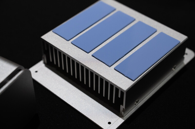 Illustration of a thermoelectric cooler module with blue semiconductor plates mounted on a finned metal heatsink.