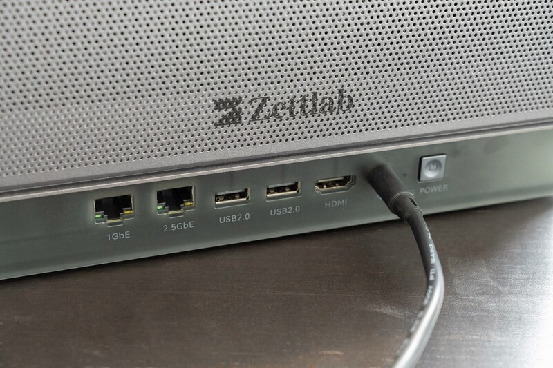Close-up of monitor rear ports including Ethernet, USB 2.0, and HDMI connections with attached cables.