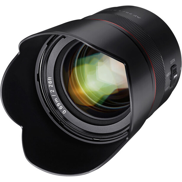 Fast telephoto lens with golden-tinted glass elements and black barrel, shown with hood against white background.