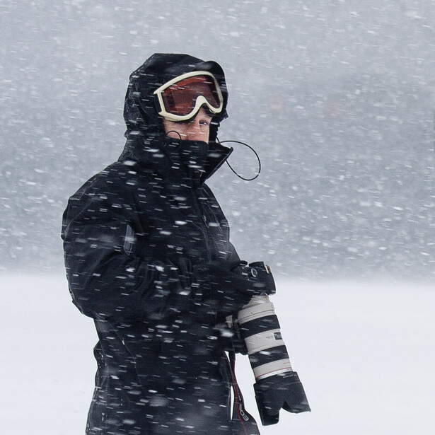 Snowboarder in black jacket and goggles during heavy snowfall.