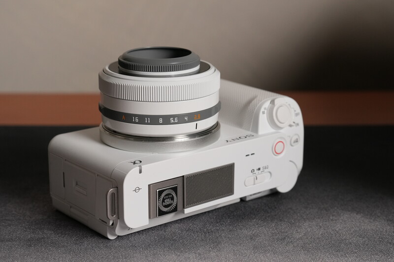 White rangefinder camera with silver and black lens mounted on top, displayed against neutral background.