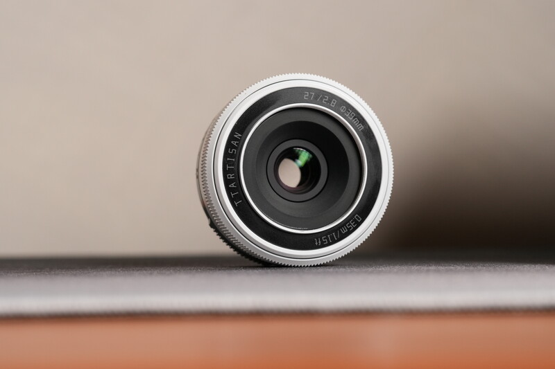 Vintage rangefinder camera lens with chrome barrel and black glass elements against neutral background.