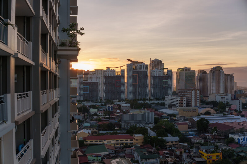 Urban skyline at golden hour with high-rise residential building in foreground and downtown cityscape at sunset.