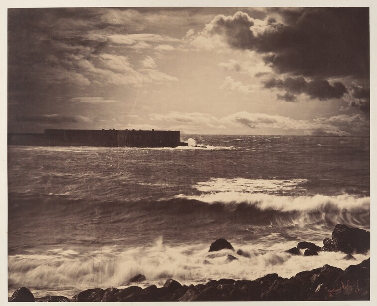 Dramatic seascape with waves crashing against rocks beneath a cloudy sky and distant structure.