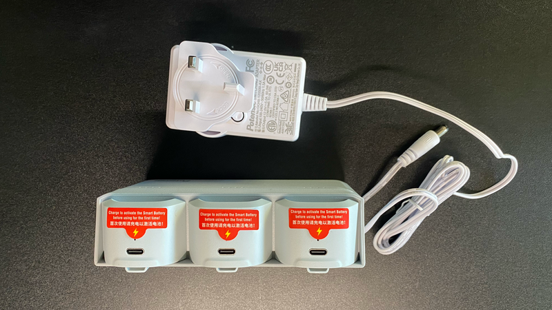 AC power adapter with three compact charging units arranged below it on dark surface.