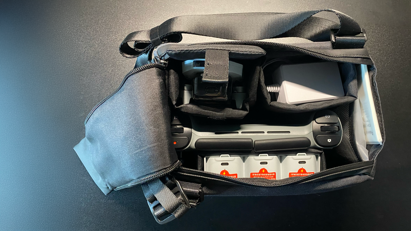 Open camera bag with compartments containing lenses, batteries, cables, and accessories arranged neatly inside.