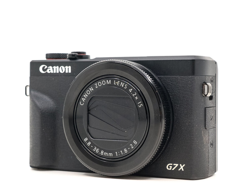 Canon G7X compact camera with Canon zoom lens and articulating grip handle against white background.
