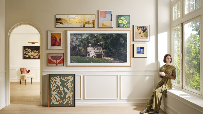 Gallery wall with mixed framed artwork and a large landscape photograph in a bright, minimalist interior space.