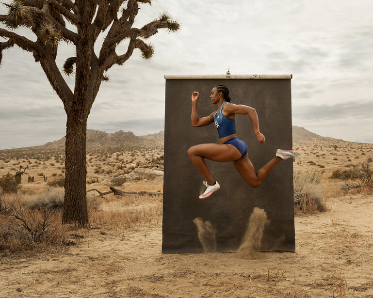 Runner in mid-stride leaping through a large black portal in a desert landscape.