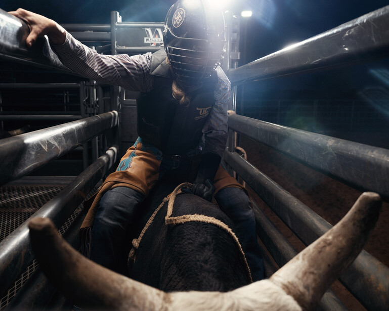Person in protective gear inside a large industrial pipe, illuminated by bright work lights.