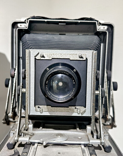 Vintage large format camera with accordion bellows and front-mounted lens element viewed from above.