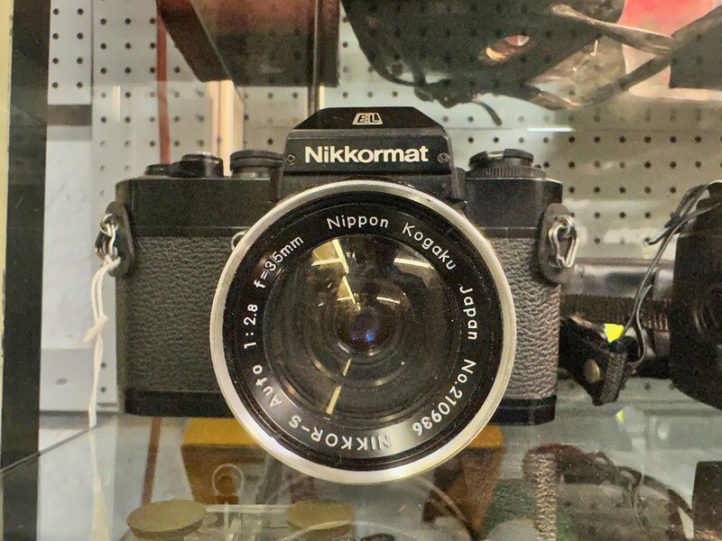 Nikkormat vintage film camera with Nippon Kogaku lens on retail shelf.