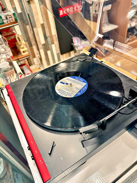 Vinyl record playing on a turntable with white base and tonearm positioned over black disc.