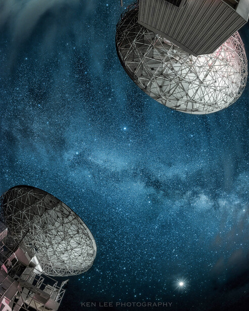 Two satellite dishes silhouetted against a starry night sky with the Milky Way visible.